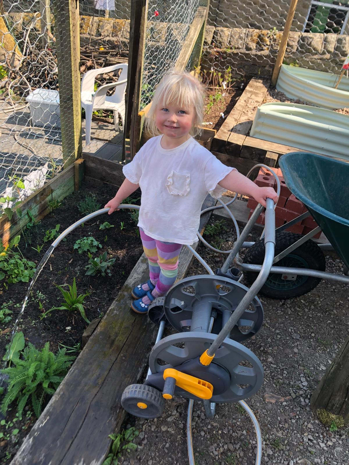 A small gardener watering the beds