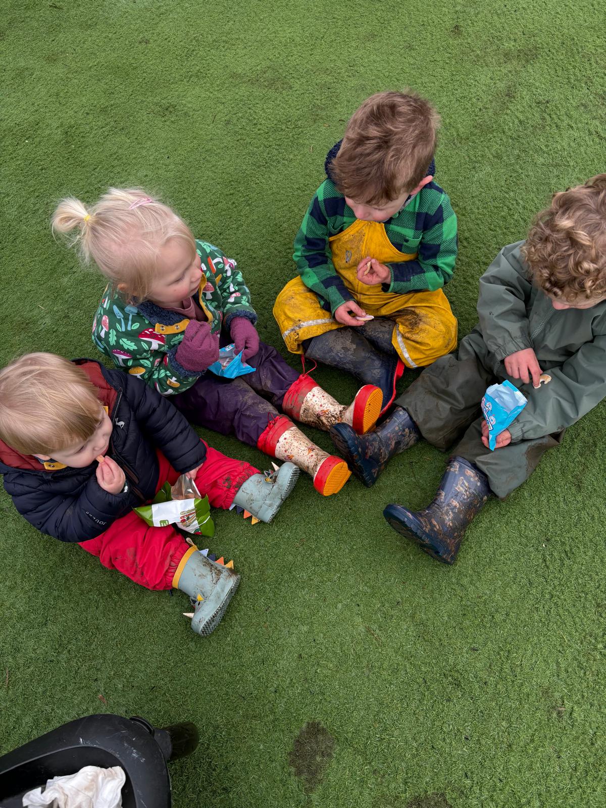 Children eating snacks in muddy boots
